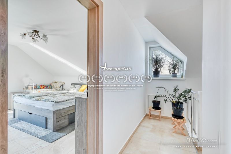 Dachbodenschlafzimmer mit Bett und Fenster, Pflanzen auf der Treppe, Einfamilienhaus.