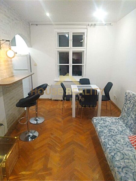 Essbereich mit weißem Tisch, grauen Stühlen und einem Boden in Holzoptik in einer Zweizimmerwohnung.