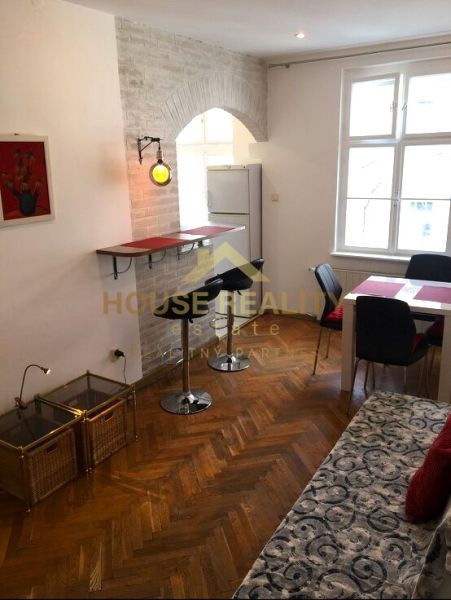 Wohnzimmer einer Zweizimmerwohnung mit Holzboden, Bar und Esstisch.