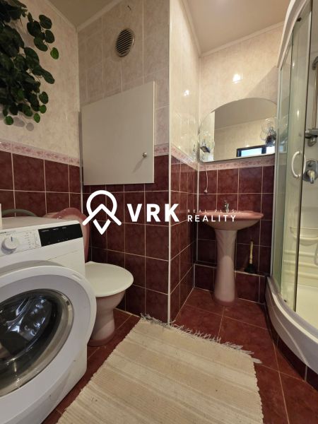 Badezimmer mit Dusche, Waschmaschine und Waschbecken in einer 4-Zimmer-Wohnung.