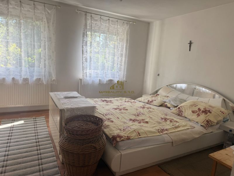 Schlafzimmer in der Hütte mit Bett, Teppich, weißer Kommode und Vorhängen, Boden mit Holzdekor.