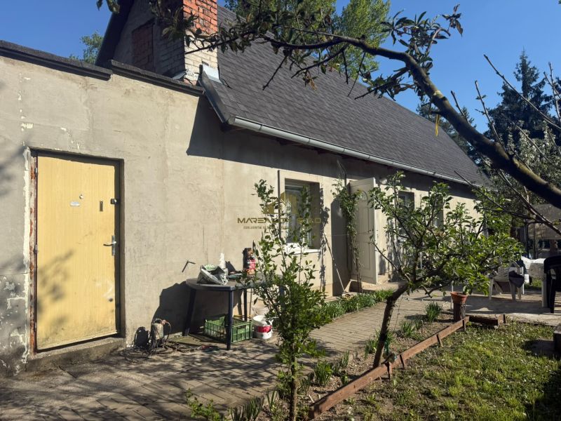 Vor dem Haus in der Straße Sekule in Sekule stehen Bäume und Gartenmöbel.