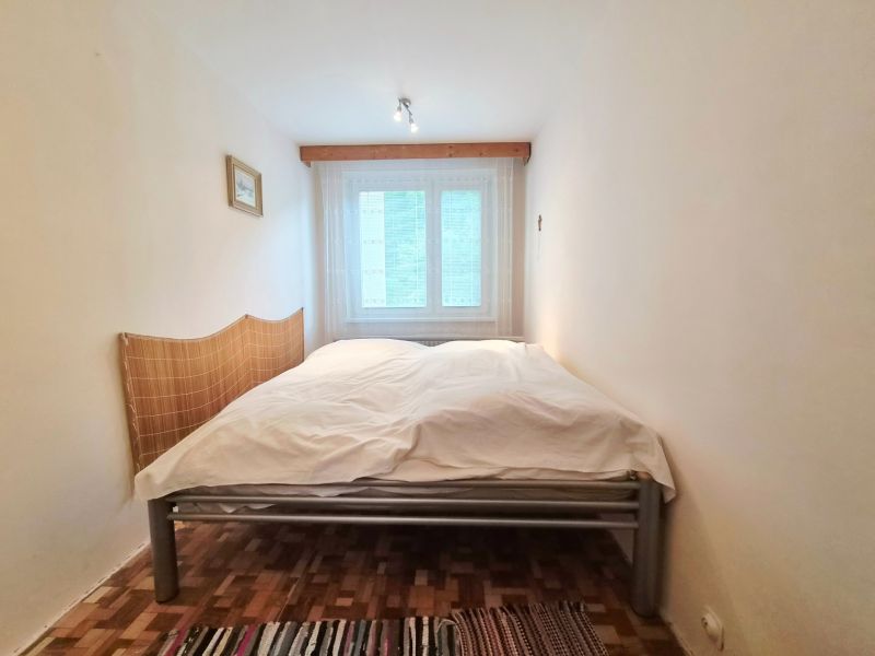 Schlafzimmer in einer 2-Zimmer-Wohnung mit Doppelbett und Boden in Holzoptik.