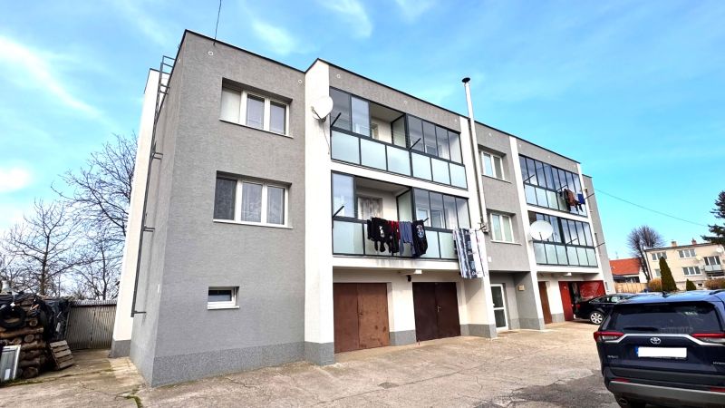 Ein dreistöckiges Wohnhaus mit Balkonen und Autos in Hlboké.
