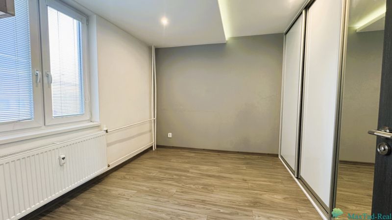 Ein leerer Raum mit einem Schrank und einem Boden in Holzoptik in einer 4-Zimmer-Wohnung.