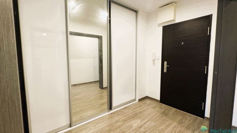 Eingangsbereich in einer 4-Zimmer-Wohnung mit weißem Schrank und Boden in Holzoptik.