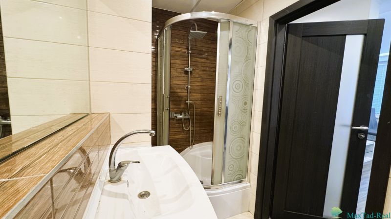 Badezimmer mit Badewanne, Dusche und dunkler Tür in einer 4-Zimmer-Wohnung.