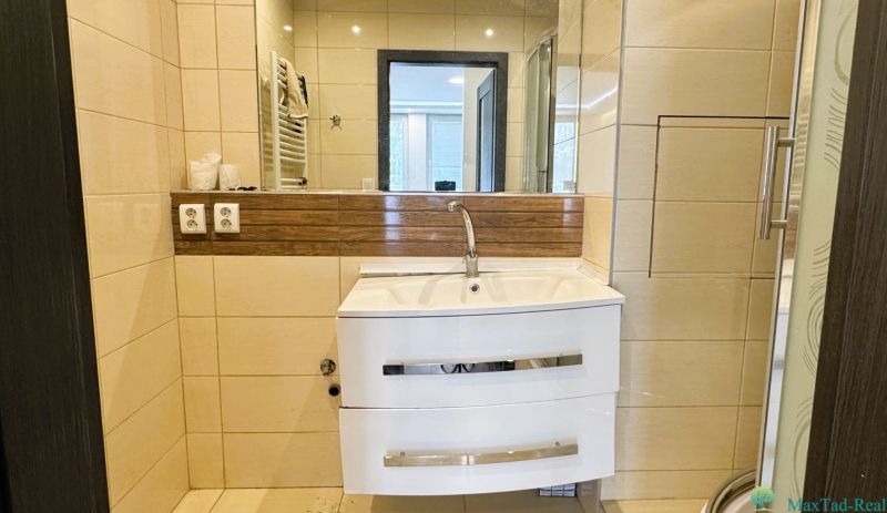 Badezimmer mit Waschbecken, Spiegel und Duschkabine in einer 4-Zimmer-Wohnung.