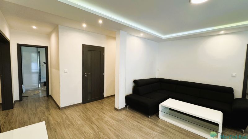 4-Zimmer-Wohnung mit Sofa, Tisch und Boden in Holzoptik.