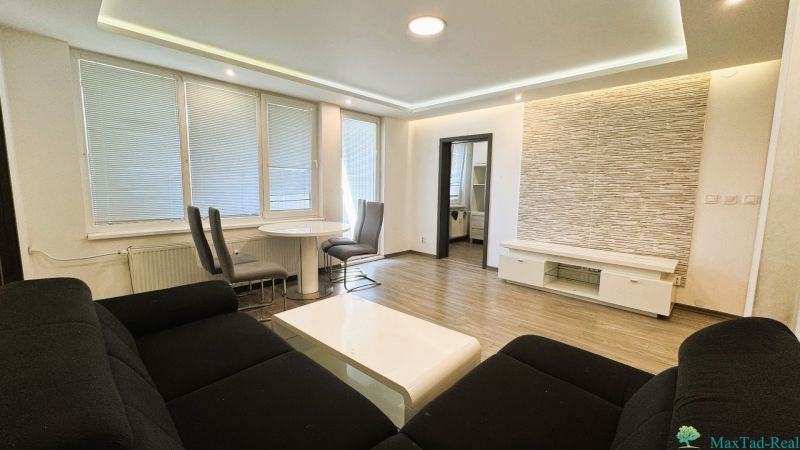 Wohnzimmer einer 4-Zimmer-Wohnung mit Holzboden, Sofa und Essecke.