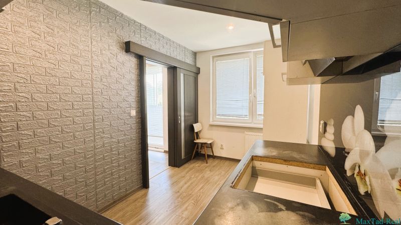 Küche in einer 4-Zimmer-Wohnung mit Holzboden und Ziegelverkleidung an der Wand.