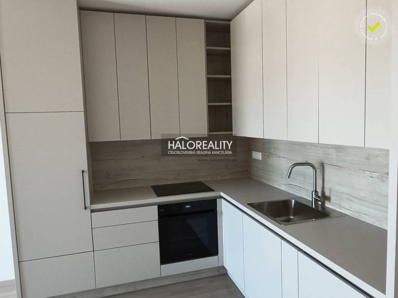 Küche in einer Einzimmerwohnung mit weißen Schränken und einem Boden in Holzoptik.
