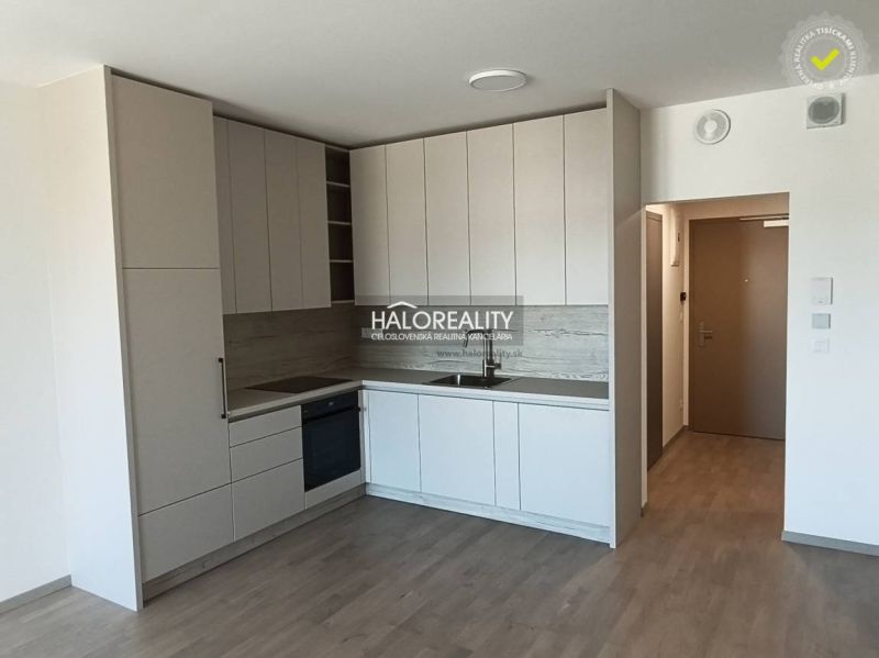 Küche in hellen Farbtönen mit Holzboden in einer Einzimmerwohnung.