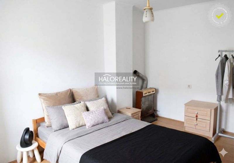 Ein Schlafzimmer in einem Einfamilienhaus mit einem bequemen Bett, einer Kommode und einem Kleiderständer.