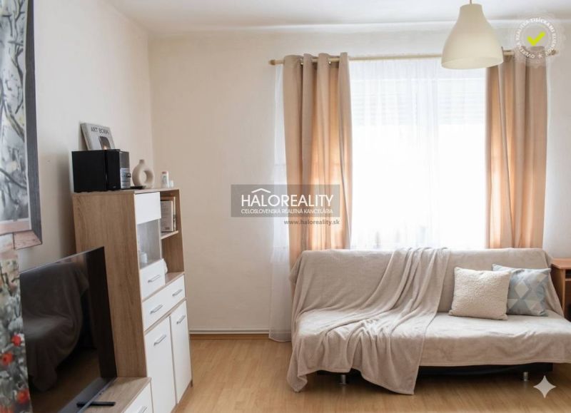 Wohnzimmer in einem Einfamilienhaus mit Holzboden und hellen Vorhängen.