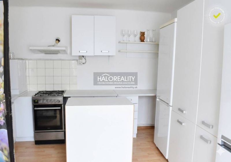 Küche in einem Einfamilienhaus mit weißen Schränken und einem Boden in Holzoptik.