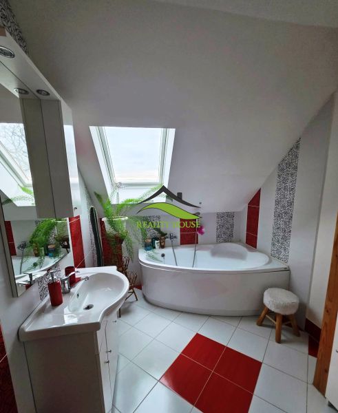 Badezimmer in einem Einfamilienhaus mit Badewanne und Dachfenster, rot-weiße Fliesen.