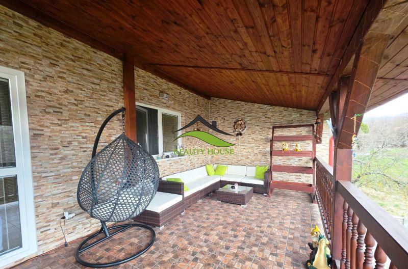 Die Terrasse des Einfamilienhauses in Klokočov mit einem Hängesessel und Korbmöbeln.