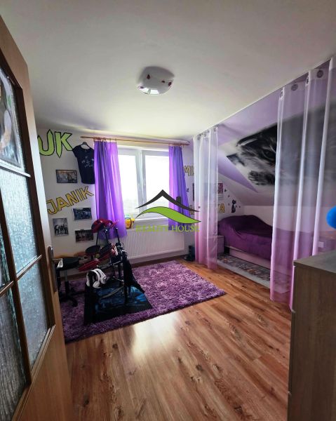 Kinderzimmer mit lila Vorhängen, Teppich, Bett, Boden mit Holzdekor.