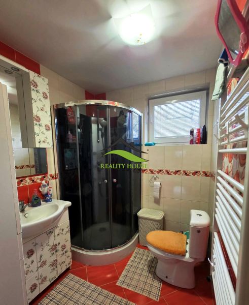 Badezimmer mit einer Eckdusche, Toilette und Blumendekor in einem Einfamilienhaus.