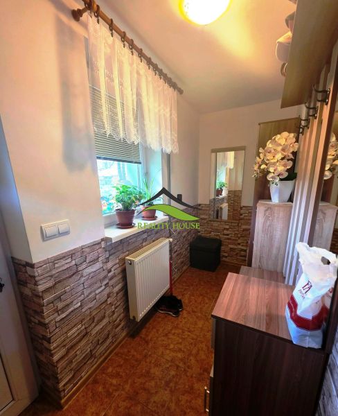 Kompakter Flur in einem Einfamilienhaus mit Ziegelverkleidung und Blumen auf der Fensterbank.