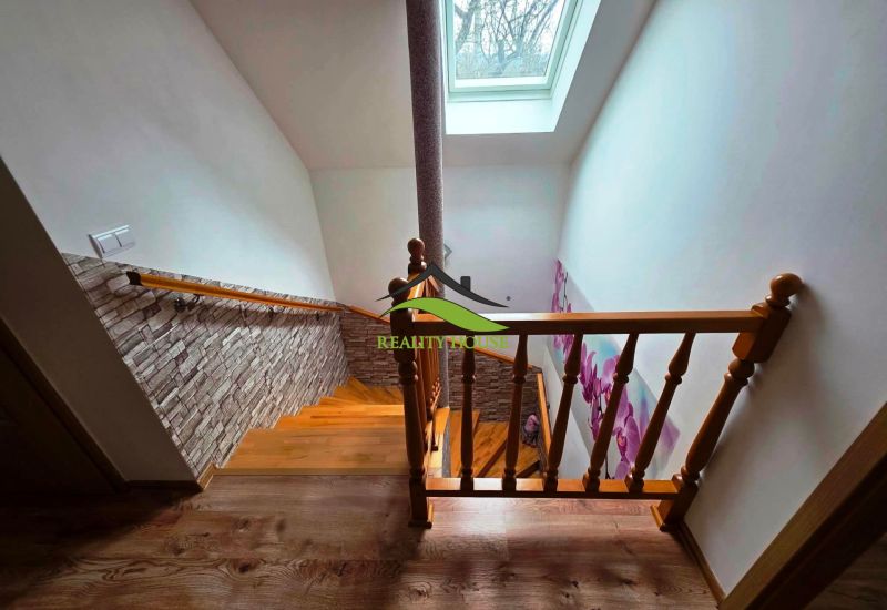 Eine Treppe mit Holzdekor, einer Blumen-Tapete und einem Dachfenster in einem Einfamilienhaus.