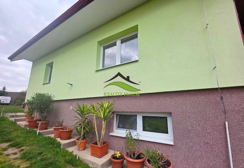 Die Fassade des Einfamilienhauses in Klokočov mit Blumenkästen und gepflegtem Grün im Hof.