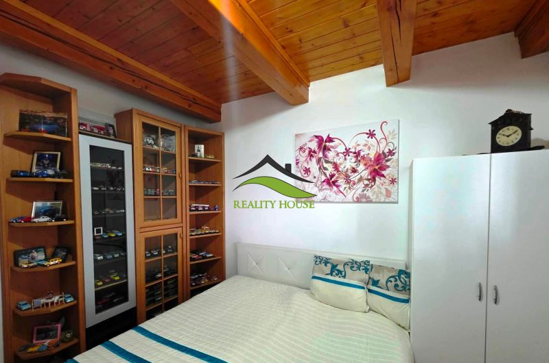 Schlafzimmer in einem Einfamilienhaus mit einer Vitrine für Automodelle und einer Holzdecke.