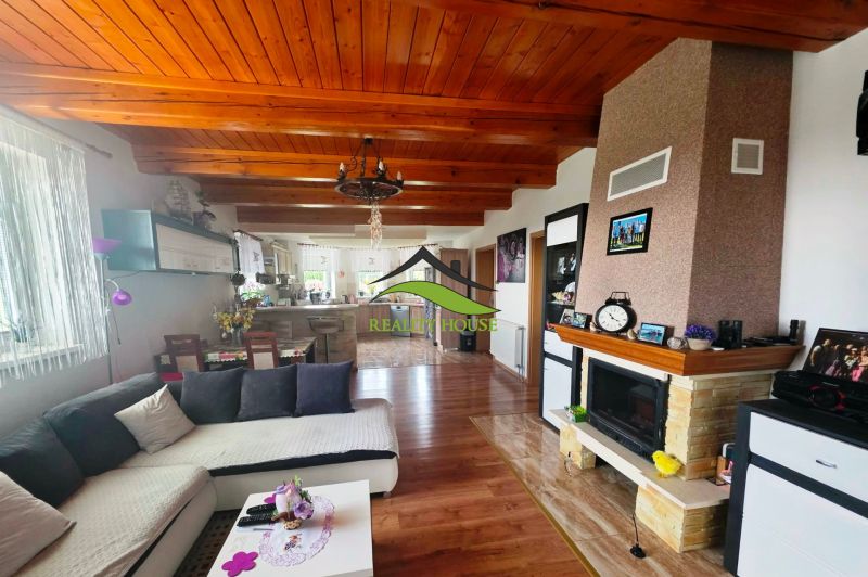 Wohnzimmer mit Küche, Kamin und Holzboden in einem Einfamilienhaus.