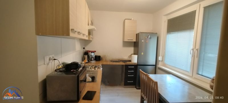 Küche in einer 2-Zimmer-Wohnung mit Geräten, Esstisch und großen Fenstern.