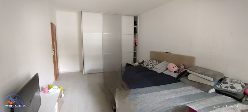Schlafzimmer in einer 2-Zimmer-Wohnung mit Schiebetürenschrank und Bett, Boden mit Holzdekor.