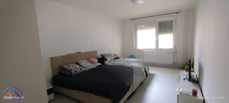 Schlafzimmer in einer 2-Zimmer-Wohnung mit großem Fenster und Bett.
