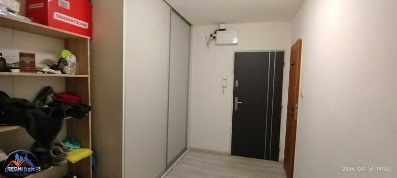 Der Flur in einer 2-Zimmer-Wohnung mit einem Einbauschrank und Regalen zur Aufbewahrung.