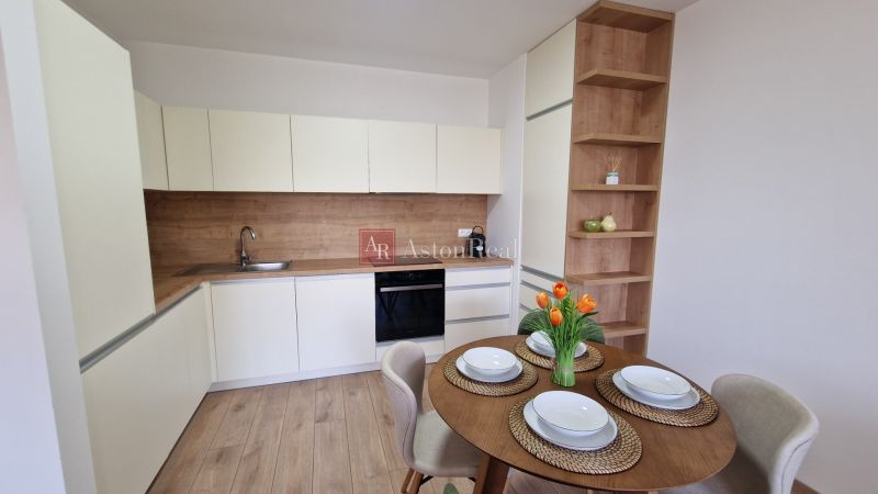 Küche in einer 2-Zimmer-Wohnung mit Tisch und Boden in Holzoptik.