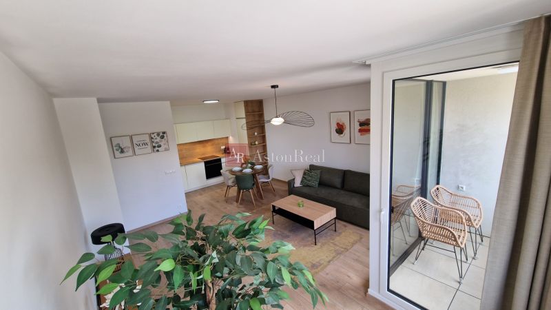 Innenraum einer 2-Zimmer-Wohnung mit Holzboden, modernen Möbeln und Balkon.