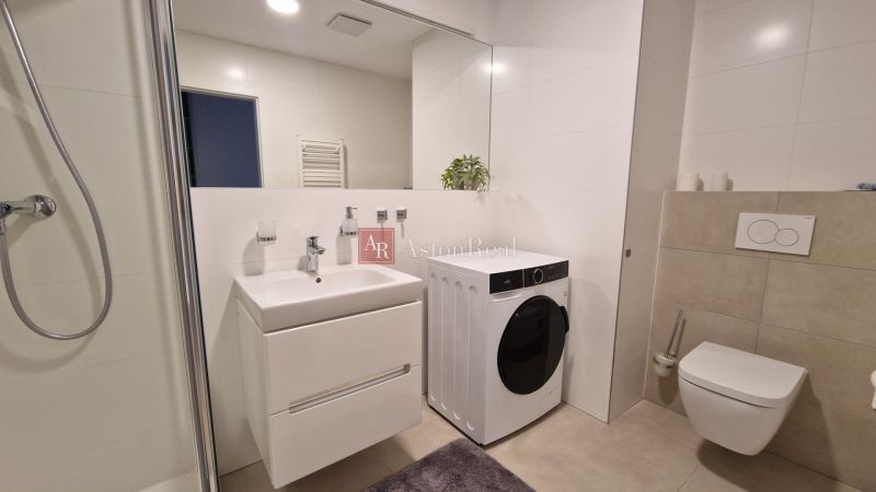 Badezimmer in einer 2-Zimmer-Wohnung mit Waschmaschine, Dusche und Waschbecken.