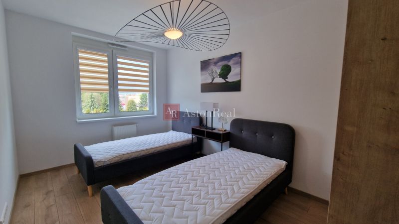Schlafzimmer in einer 2-Zimmer-Wohnung mit zwei Betten und einem Boden in Holzoptik.