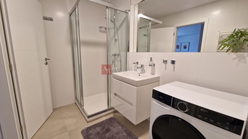 Badezimmer in einer 2-Zimmer-Wohnung mit Dusche, Waschbecken und Waschmaschine.