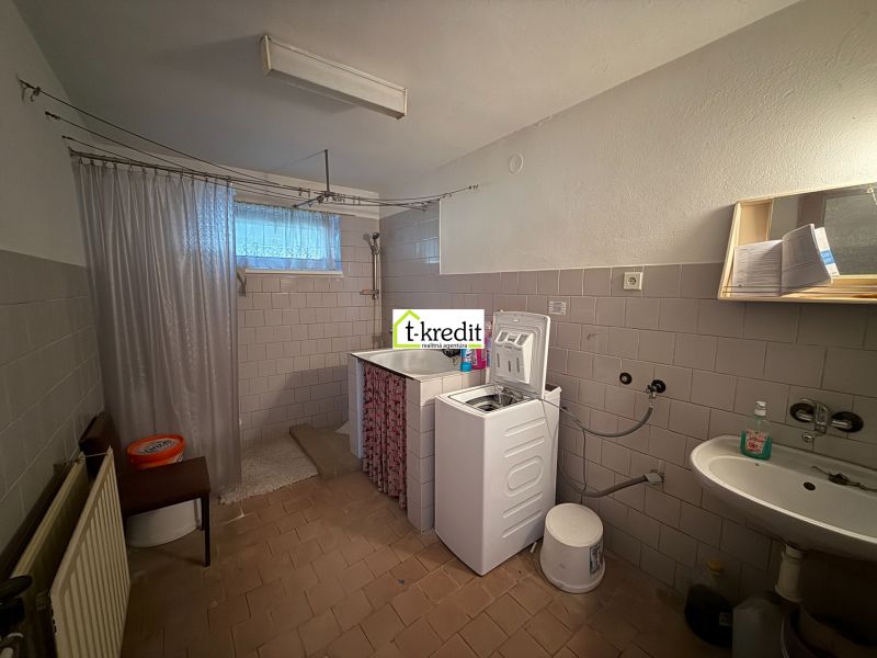 Badezimmer mit Waschbecken, Waschmaschine und Dusche in einem Einfamilienhaus.
