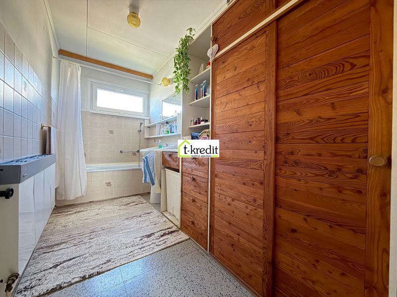 Badezimmer mit Holzschränken und Badewanne in einem Einfamilienhaus.