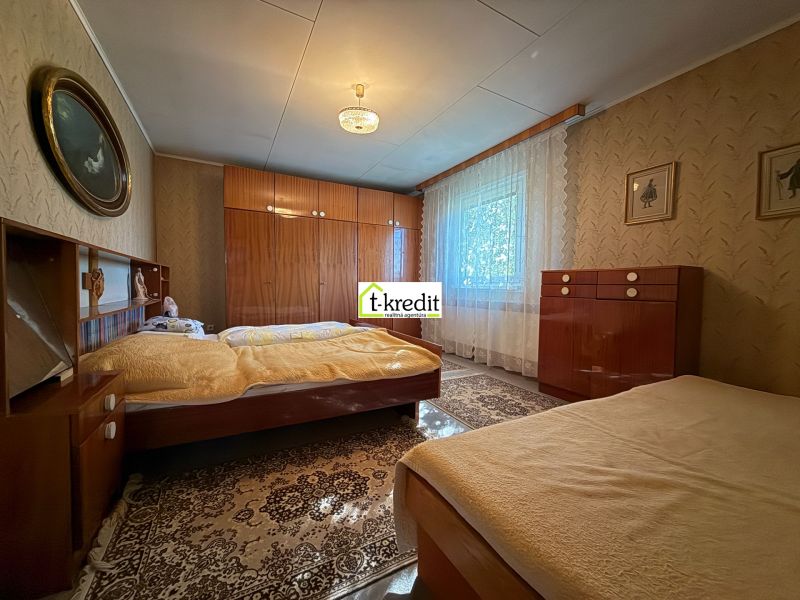 Schlafzimmer in einem Einfamilienhaus mit klassischen Möbeln, Boden mit Holzdekor, Vorhänge an den Fenstern.