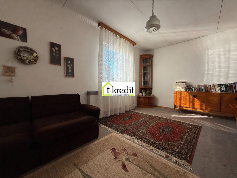 Wohnzimmer in einem Einfamilienhaus mit Teppichen, Sofa und Holzmöbeln.