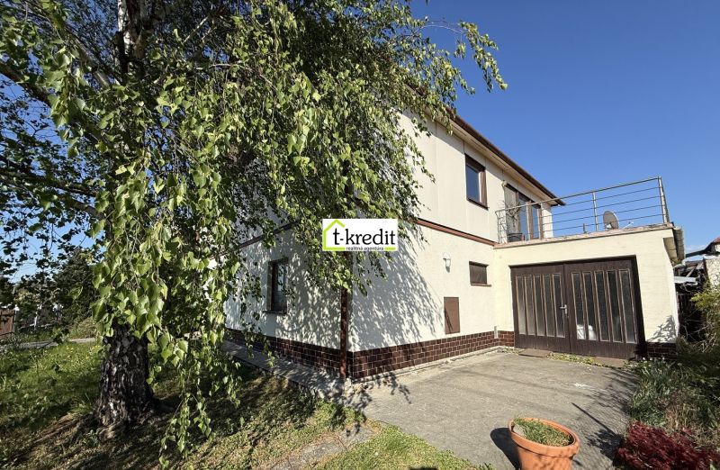 Ein Einfamilienhaus in Zlaté Moravce mit Garage und Terrasse, umgeben von Grün und Bäumen.