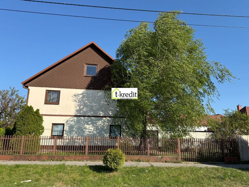 Ein Einfamilienhaus in Zlaté Moravce, ein Garten mit Bäumen, ein Zaun und blauer Himmel.
