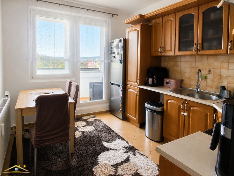 Küche in einer 3-Zimmer-Wohnung mit Holzschränken, Esstisch und großem Fenster.