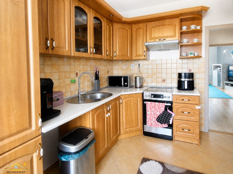 Küche in einer 3-Zimmer-Wohnung mit Holzschränken und einem Boden in Holzoptik.