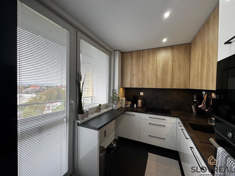 Küche in einer 3-Zimmer-Wohnung mit Holzboden, weißen Jalousien und Ausblick.