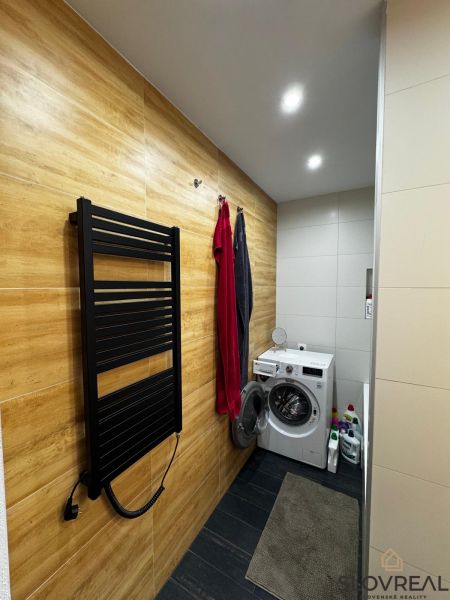 Badezimmer mit Waschmaschine, Boden mit Holzdekor, Handtuchhalter in einer 3-Zimmer-Wohnung.