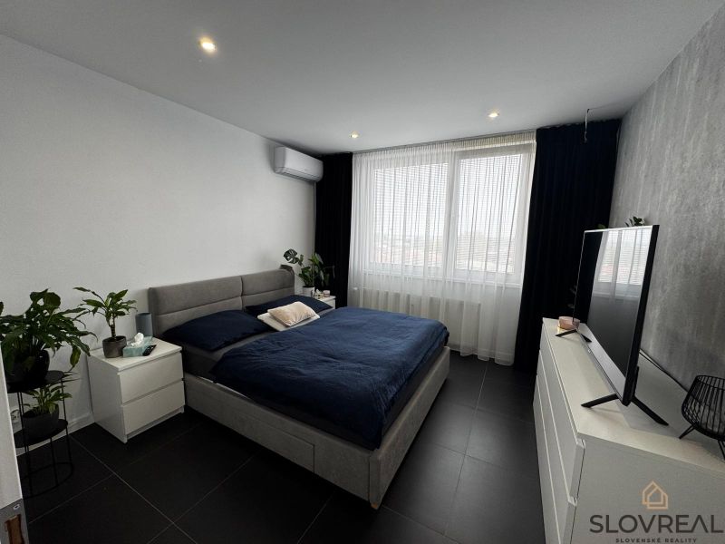 Schlafzimmer in einer 3-Zimmer-Wohnung mit einem großen Bett, Fernseher und Zimmerpflanzen.
