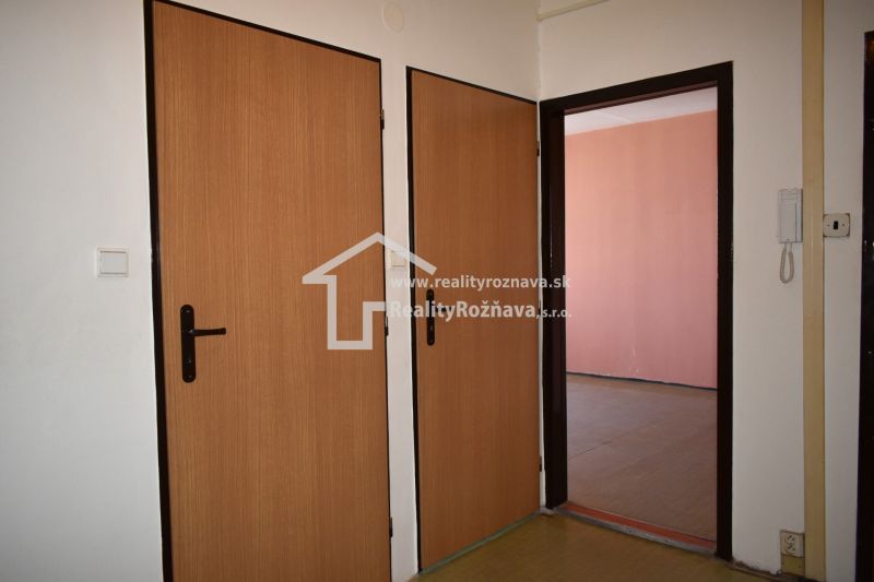 Innenraum einer 3-Zimmer-Wohnung mit Türen in Holzdekor und einem Telefon an der Wand.